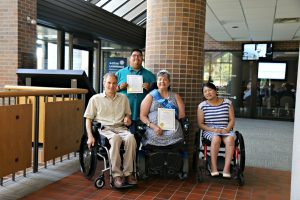 4 adults with various disabilities in the lobby of a City Hall