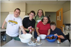 young adults with various disabilities gathered around a table with food