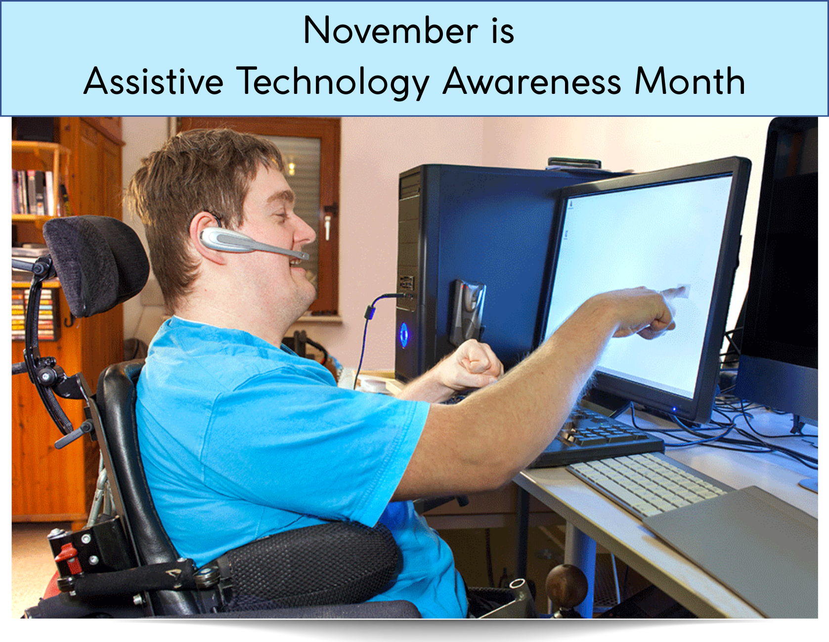 Image of a young adult using a wheelchair sitting at a computer desk wearing a headset and pointing at  a computer scre
