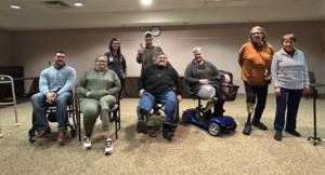 a group of people with limb loss gather for a group photo in a conference room setting