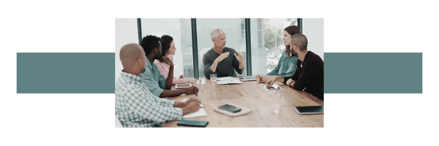 a group of adults sitting at a conference style table in a meeting